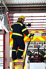 Image showing Firefighter, ladder and safety worker with hose truck at a fire station with emergency service employee. Uniform, firetruck and helmet of a fireman ready for rescue working with equipment at a job