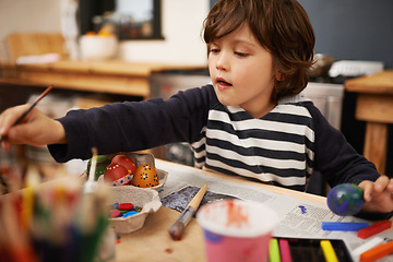 Image showing Happy child, creative and color painting of eggs and celebration of easter holiday in home. Young, artist and boy with inspiration for learning craft, mural and paintbrush with supplies in kitchen