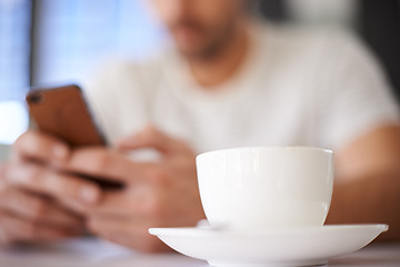Image showing Man, cup and hands for phone in coffee shop, communication and website for information. Male person, closeup and app for conversation, social media and remote work in restaurant for research by latte