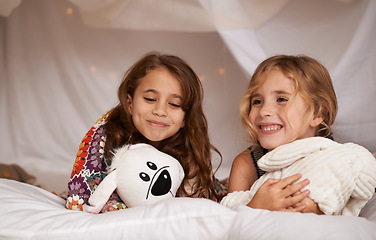 Image showing Happy, sleepover and children in bedroom for playing, bonding and relax with toys in home. Night, friends and young girls on bed in tent or blanket fort for childhood, fun and happiness together