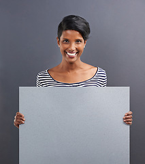 Image showing Happy woman, portrait and presentation with billboard for advertising or marketing on a gray studio background. Young female person or Indian with smile, poster or notification sign on mockup space