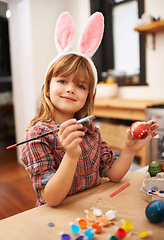 Image showing Happy girl, portrait and paint with easter egg for colorful art, tradition or holiday crafts at home. Young child enjoying color, activity or artwork with smile, paintbrush or bunny ears at the house