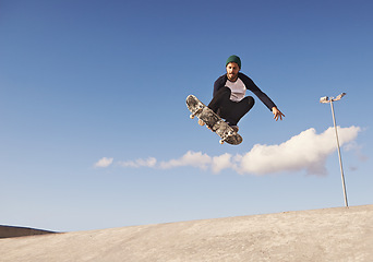 Image showing Skateboard, blue sky and man with ramp, challenge and training for a competition, talent and sunshine. Adventure, person and skater with practice for technique or balance with fitness, energy or jump