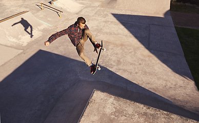 Image showing Skateboard, jump or man with ramp, challenge or training for a competition, hobby or sunshine. Adventure, person or skater with practice for technique, talent or skill with exercise, energy or cardio