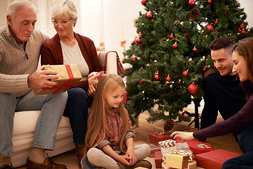 Image showing Family, christmas tree and gifts with kids, parents and grandparents together with giving in living room. Home, happy and present with holiday and celebration at a party with love, care and bonding