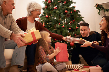 Image showing Family, present and christmas in home with love, giving and care together at holiday event. Happy, smile and tree with celebration, child and marriage in a house with grandparents and festive gift