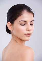 Image showing Calm woman, face and skincare with cosmetics or facial treatment on a gray studio background. Young female person, brunette or model with smile in satisfaction for beauty, makeup or spa cosmetology