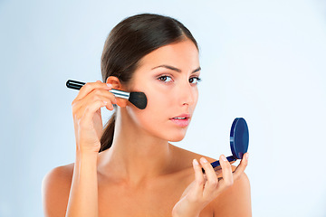 Image showing Portrait, woman and makeup with brush and compact for foundation or blush with beauty on blue background. Powder, cosmetics and product for cosmetology with tools, skin glow and facial in studio