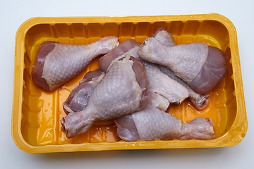 Image showing raw chicken legs in a plastic container on a white