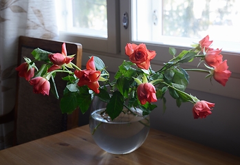 Image showing roses in a glass vase on a wooden table