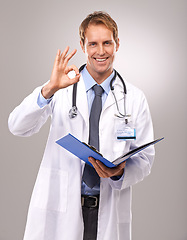 Image showing Clipboard, okay sign and portrait of doctor in studio for medical review, documents and report. Healthcare, hospital and man with hand gesture for success, good news and consulting on gray background