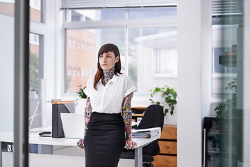 Image showing Tattoos, thinking and business woman in office with planning, brainstorming or ideas face. Grunge, reflection and professional edgy female creative designer with ink skin standing in modern workplace