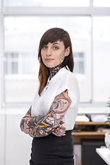 Image showing Tattoos, crossed arms and business woman in office with serious, pride and confident attitude. Grunge, professional and portrait of edgy creative designer with ink skin standing in modern workplace.