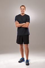 Image showing Studio, portrait or athlete with arms crossed or fitness for running workout, exercise or health wellness. Grey background, proud runner or sports man ready to start training with confidence or smile