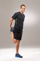 Image showing Portrait, man or stretching as flexibility, mobility or exercise for wellness, workout or training. Happy, runner or athletic male person as strong, proud or muscle care in studio on grey background