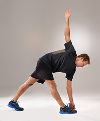 Image showing Man, fitness or training with stretching, mobility or workout as exercise, self care or strength. Runner, athletic person or sportsman in muscle, flexibility or warm-up in studio on grey background