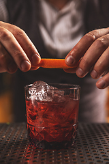 Image showing Bartender twisting orange peel over a craft cocktail
