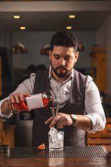 Image showing Professional bartender crafting cocktail at bar