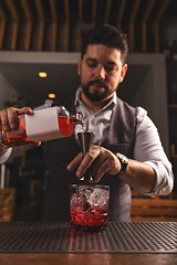 Image showing Professional bartender pouring a cocktail at bar