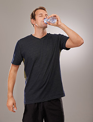 Image showing Healthy, studio or man drinking water for fitness, hydration or workout break isolated on grey background. Tired person, training or thirsty athlete with fresh h2o liquid drink for exercise or detox