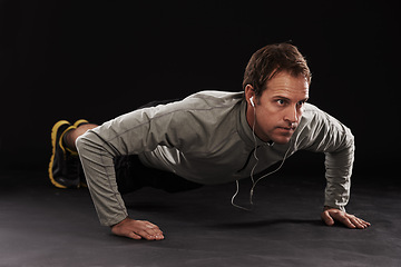 Image showing Man, face and push up with workout or music in studio with exercise, fitness and training with earphones. Athlete, person and bodybuilder on floor with audio, radio and podcast on black background