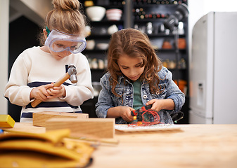 Image showing Children, construction and building in workshop with tools, play and game in kitchen of home. Girls, hammer and safety glasses for wood project on weekend, carpentry and woodworking or manufacture