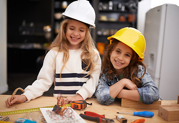 Image showing Children, construction and portrait in workshop with tools, play and game in kitchen of home. Girls, hardhat and protection for wood project on weekend, carpentry and woodworking or manufacture