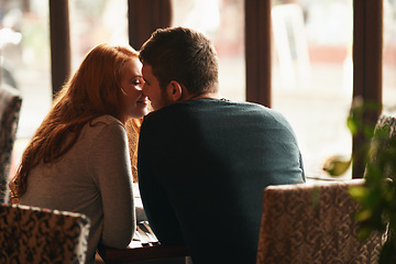 Image showing Couple, happiness and kiss on date at restaurant for bonding, romance or healthy relationship with rear view. Man, woman and affection at coffee shop with smile, trust or love on anniversary vacation