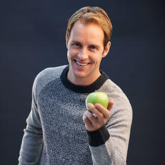 Image showing Man, apple and smile in studio portrait with choice for detox, diet or health by dark background. Person, model and happy with green fruit with pride for decision, vegan nutrition and organic snack