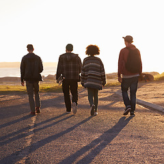 Image showing Walking, sunset and back of friends on vacation, travel or holiday together with skateboard. Summer, evening and group of young people by outdoor ocean or sea on weekend trip for bonding in nature.