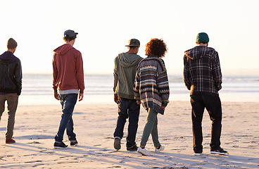 Image showing Friends, walking and beach for sunset, sand and sea with ocean for nature, behind and peace outdoor. Young people or group together for trek and environment for summer season and warm vacation