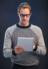 Image showing Man, glasses and tablet for reading in studio with connection, contact and fashion by dark background. Person, entrepreneur and digital touchscreen, pride and confidence with app for social network