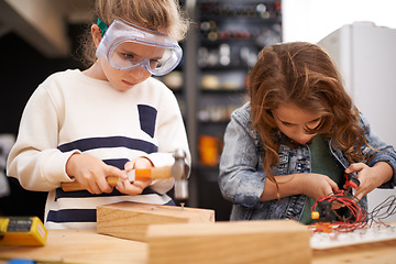 Image showing Children, construction and diy in workshop with tools, play and game in kitchen of home. Girls, hammer and safety glasses for wood project or building, carpentry and woodworking or manufacture