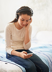 Image showing Headphones, phone and teenager listening to music on bed to relax with streaming on mobile app. Bedroom, girl and kid with technology for podcast, online and connection to internet for audio
