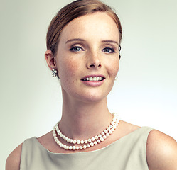 Image showing Portrait, fashion and beauty of young woman in studio isolated on a gray background. Face, freckles and skin of person in vintage clothes for style, retro or elegance with pearl necklace in Ireland