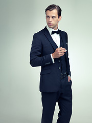 Image showing Thinking, elegant or young gentleman smoking a cigarette in studio, confidence or vintage fashion by white background. Serious, man and idea in retro suit or tuxedo, bow tie and class at formal event