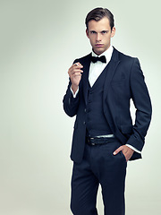 Image showing Portrait, serious or young gentleman smoke a cigarette in studio, confidence or vintage fashion by white background. Face, tobacco or man in retro suit or tuxedo, bowtie or hands in pocket for class