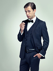 Image showing Portrait, attitude or young gentleman smoking a cigarette in studio, confidence or vintage fashion by white background. Face, serious or man in retro suit or tuxedo, bow tie or classy at formal event