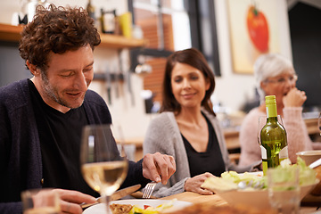 Image showing Happy, eating and family at dinner in dining room for party, celebration or event at modern home. Smile, bonding and group of people enjoying meal, supper or lunch together with wine at house.