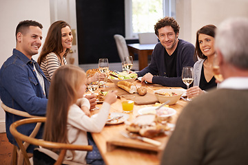 Image showing Smile, conversation and family at dinner in dining room for party, celebration or event at modern home. Happy, bonding and people enjoying meal, supper or lunch together with wine for toast at house.