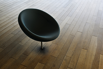 Image showing A black chair on a wood floor