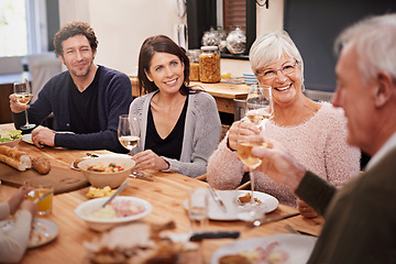 Image showing Happy, cheers and people at dinner in dining room for party, celebration or event at modern home. Smile, bonding and group of family enjoying meal, supper or lunch together with wine at house.