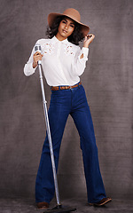 Image showing Woman, fashion and cowgirl in studio, microphone and western clothes on proud and confident singer. Musician, female person with trendy hat accessory for countryside culture, isolated on background