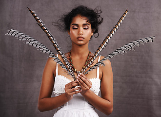 Image showing Fashion, studio and face of boho woman with feather, relax and modern cosmetics style. Creative, unique culture and girl with indigenous aesthetic, serious or natural makeup on grey background