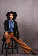 Image showing Portrait, cowgirl or woman in studio, wild west culture and cool fashion in clothing on grey background. Young female person, western lady and stylish model with pride, boho style and chair stool