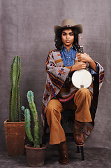 Image showing Portrait, cowgirl or woman with instrument for music in studio and cool fashion or clothing on grey background. Native American person, western and model with plants, boho style and banjo for a song