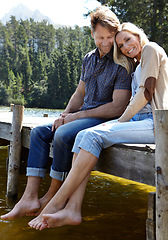 Image showing Couple, lake and sitting on pier, portrait and happy with care on vacation, relax or memory in summer. Man, woman and river with smile, care or bonding with connection for love on holiday in Colorado