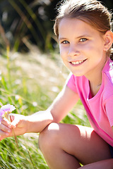 Image showing Girl, grass and portrait of kid with flower in nature for spring enjoyment, vacation and development. Happy, child and relax with plant in meadow for peace, holiday and adventure in green park