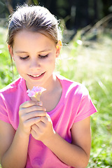 Image showing Smile, kid and girl with flower in nature for summer vacation, development and relax in grass field. Garden, happy and child with plant for sunshine, holiday and adventure in green environment