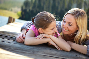 Image showing Mother, daughter and relax on pier by a lake, bonding in nature or camping with holiday, travel and family time. Love, support and trust, woman and young girl outdoor for adventure and fresh air